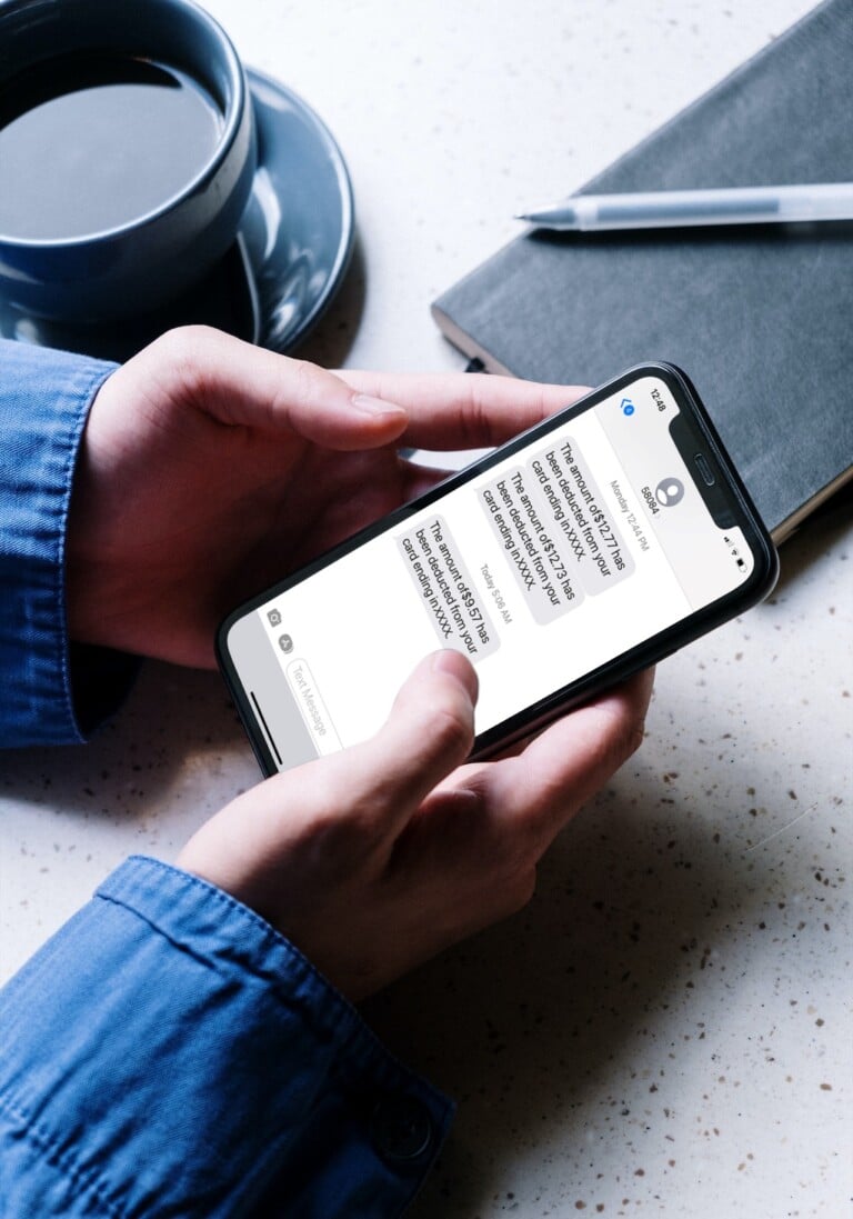 Mobile text alert on iPhone 11 in the hands of a man beside the notepad