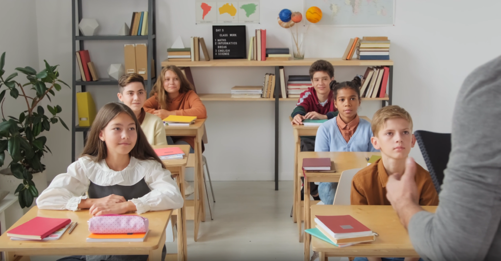 students sitting in classroom listening to teacher