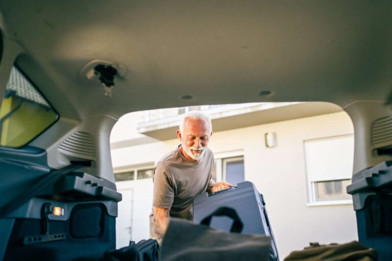 One senior man travel concept male take stuff belongings from the back or put suitcase in trunk of the car while moving to travel or arrive to destination real people copy space